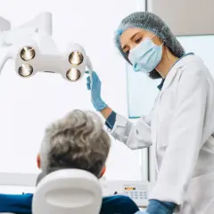 Dentystka w masce i rękawiczkach przygotowuje się do zabiegu. Pacjent siedzi na fotelu. Czy dentysta może wystawić L4?
