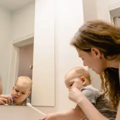 Mama pomaga dziecku myć zęby. Maluch ma lekki odruch wymiotny przy myciu zębów, ale mama go uspokaja.