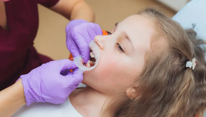 Dziecko u dentysty, przygotowanie do lakowania zębów. Sprawdź, jaka jest lakowanie zębów cena.
