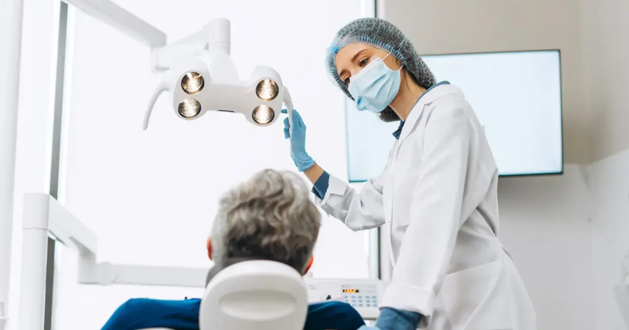 Dentystka w masce i rękawiczkach przygotowuje się do zabiegu. Pacjent siedzi na fotelu. Czy dentysta może wystawić L4?