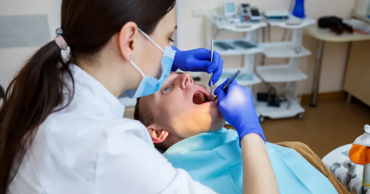 Dentystka bada zęby pacjenta. Czy dentysta może wystawić L4? Tak, jeśli stan zdrowia pacjenta tego wymaga.